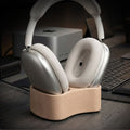Silver headphones on a wooden stand with a blurred office background