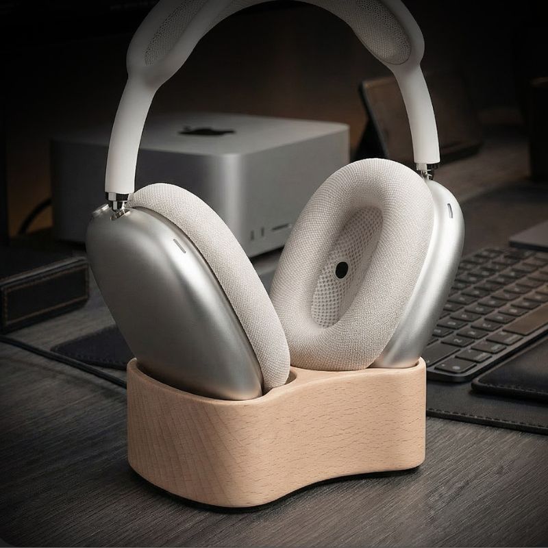 Silver headphones on a wooden stand with a blurred office background