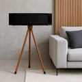 JBL L75MS Stand Holder Wood Tripod - iWoodStore Black speaker on a wooden tripod stand in a living room setting with a sofa and decorative pillow.
