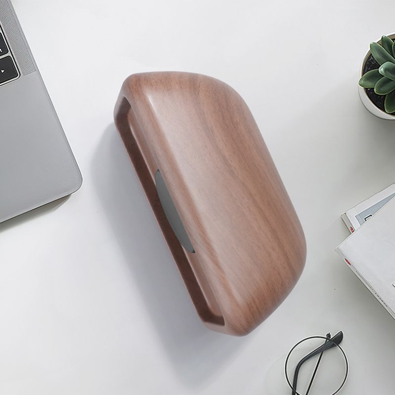 Wooden desk organizer on a white surface with a laptop and books in the background