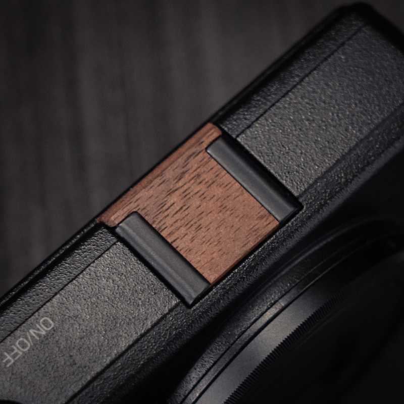 Ricoh GR4 Hotshoe Cover Wood iWoodStore Close-up of a device with a wooden switch and black casing.