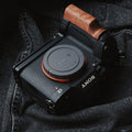 A Sony Alpha camera with a wooden handle grip and black mounting bracket, resting on dark gray denim fabric.