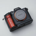 A Sony mirrorless camera body with a wooden grip attachment, resting on a textured gray denim fabric background.