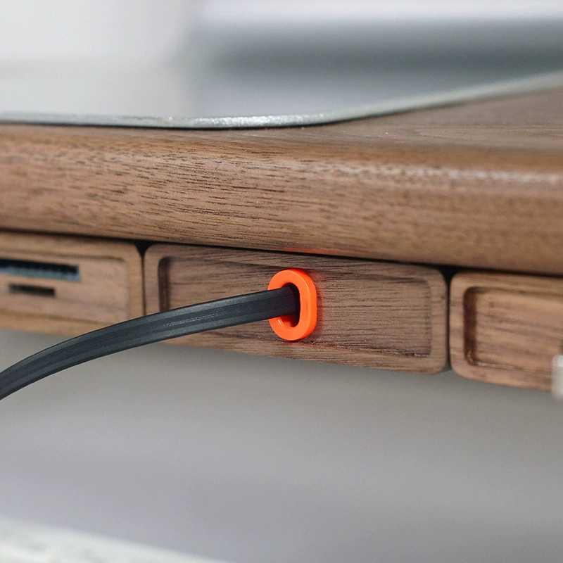 Close-up of a wooden device with an orange plug inserted into it. Wood Telescopic Retractable Data Cable Charging Cable For Desk iWoodStore
