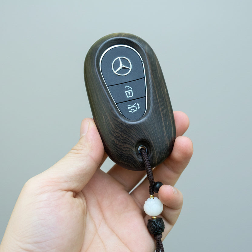 Hand holding a Mercedes-Benz key fob with a gray background